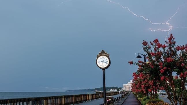 Éclair frappant le ciel au-dessus d'une promenade en bord de mer, illustrant les derniers orages intenses.