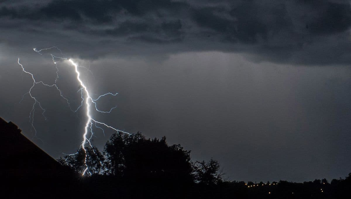 Éclair frappant le sol sous un ciel d'orage sombre, symbolisant une alerte orange en France.