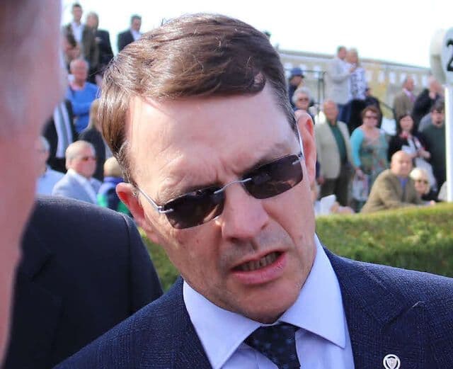 Close-up of a man in sunglasses, likely trainer Francis-Henri Graffard, known for his strategic approach to international racing.