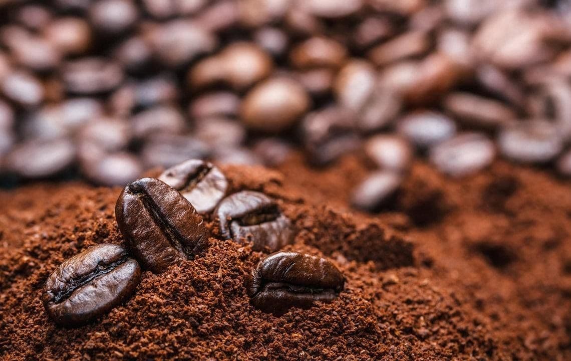 Close-up of roasted coffee beans and ground coffee, illustrating the impact of surging global coffee prices on the final product.