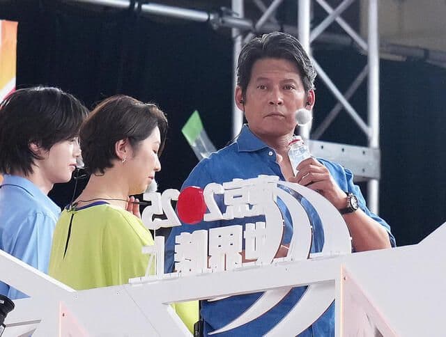 Commentators or officials at a track and field World Championships event with Japanese text on a sign.
