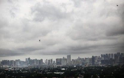 Dark clouds over Metro Manila skyline, symbolizing impending rainfall warnings and their impact on daily life.