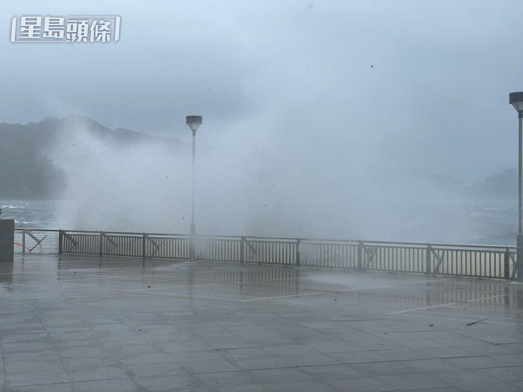 De grandes vagues s'écrasent contre un mur de protection côtier sous un ciel orageux, illustrant la force du typhon Wipha.