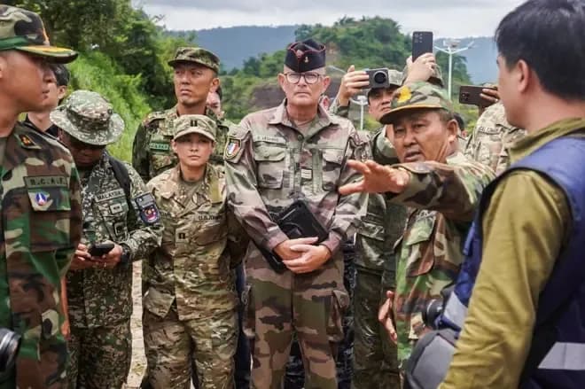 Des diplomates et militaires internationaux inspectant une zone frontalière, représentant la diplomatie et la coopération en matière de sécurité en Asie du Sud-Est.