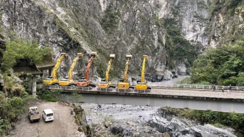 Des excavatrices sur un pont dans un paysage montagneux, évoquant la construction de régulations robustes et la réconciliation des valeurs.