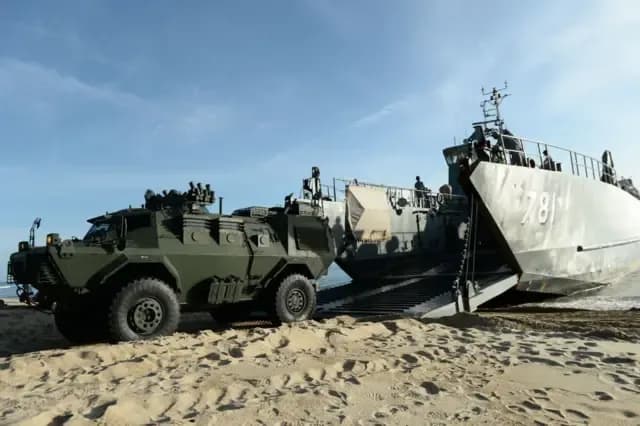 Des Marines thaïlandais déchargeant des véhicules militaires d'un navire sur une plage, illustrant la stratégie militaire maritime.