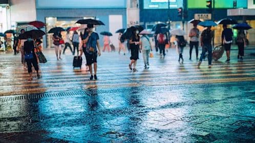 Des personnes marchant sous une pluie battante avec des parapluies dans une ville de Taïwan, illustrant l'impact des caprices du climat.