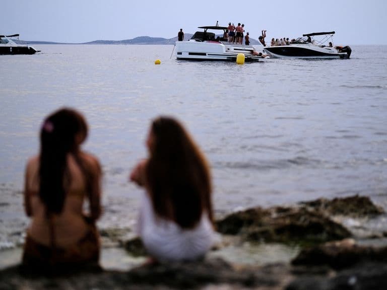 Des personnes profitent du bord de mer au crépuscule, cherchant la fraîcheur après une journée chaude.