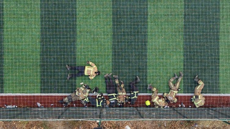 Des pompiers épuisés se reposant sur un terrain de football après des heures de lutte contre l'incendie à Bursa.