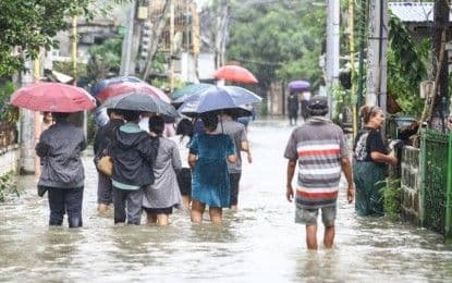 Des résidents de Calumpit, Bulacan, pataugent dans les eaux de crue, illustrant l'impact direct de l'état de calamité.