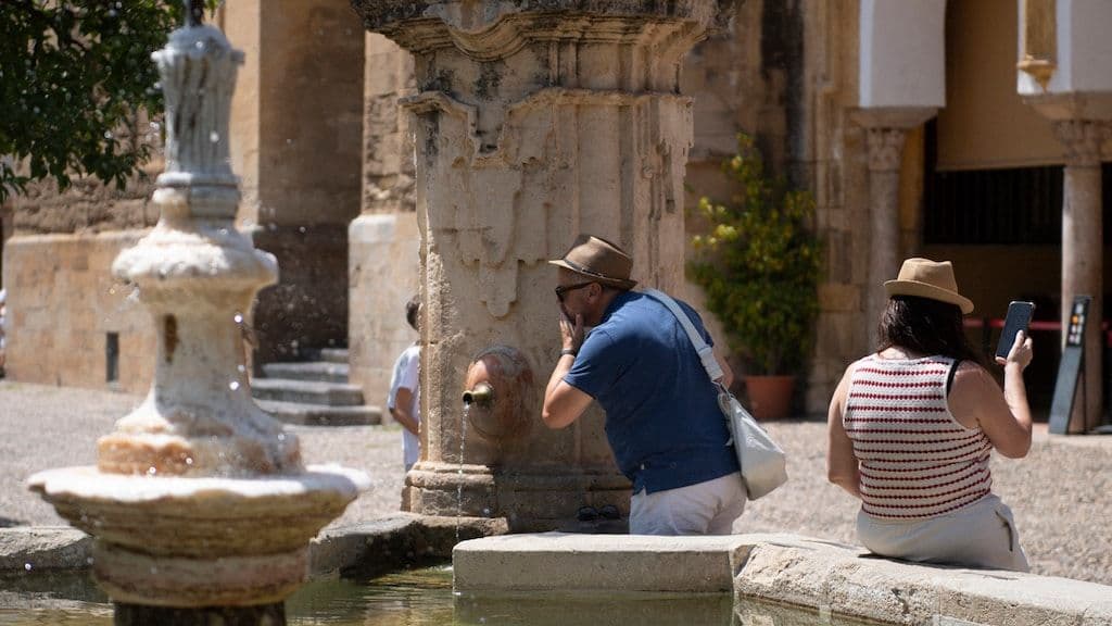 Des touristes se rafraîchissent près d'une fontaine à Cordoue sous une forte chaleur.