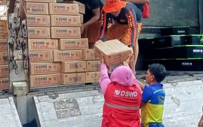 DSWD personnel distributing relief goods from a truck to affected families, highlighting community support.