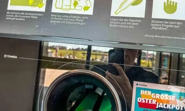 Eine Person gibt eine Pfandflasche in einen Rückgabeautomaten, symbolisierend die Reibung von Pfandsystemen, die Rauch mit seinen neuen Ohne-Pfand-Kartons vermeiden will.