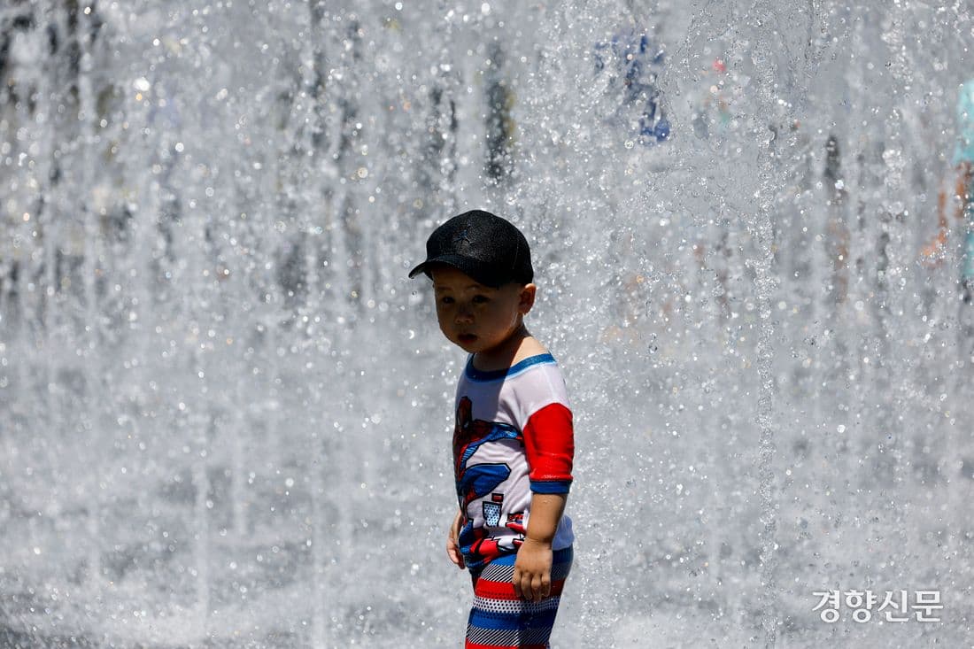 Enfants se rafraîchissant dans une fontaine publique de la place Gwanghwamun à Séoul sous une canicule extrême.