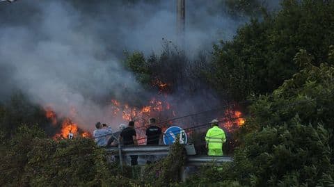 Flames erupting from vegetation near a road in Ponteceso, showing the immediate impact of the electrical spark.