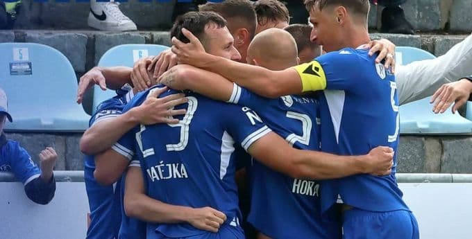 Football players in blue jerseys celebrating a last-minute victory, illustrating the unscripted drama and luck in the Chance Liga.