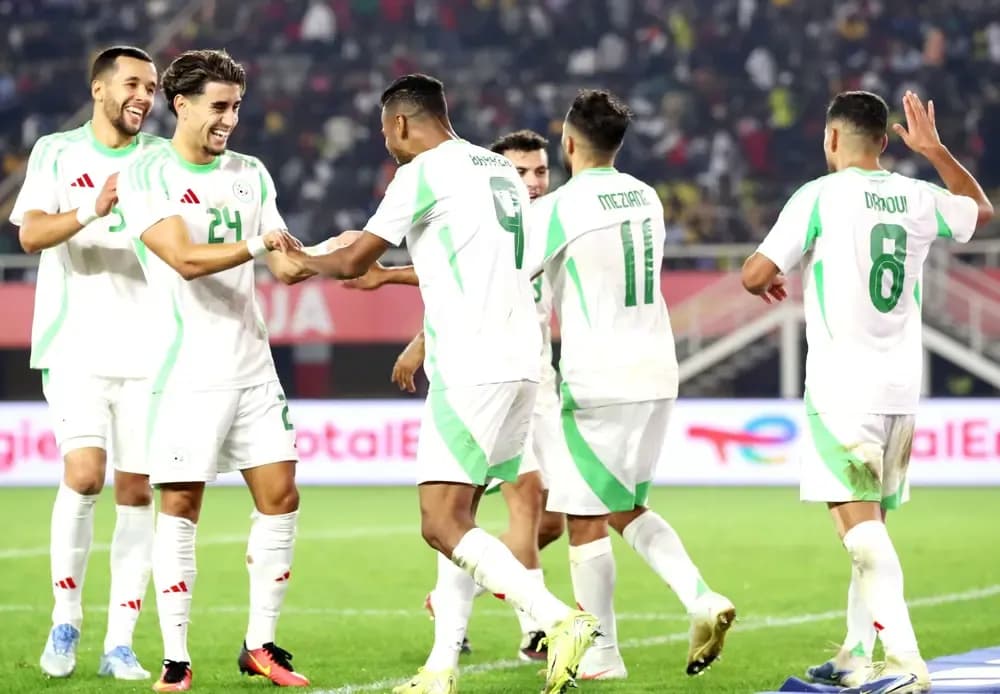 Football players in white and green jerseys celebrating a goal on the field, symbolizing the positive impact and success of African football tournaments like CHAN.