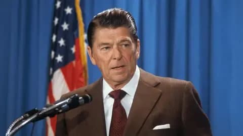Former US President Ronald Reagan at a microphone, central to the debate over his free trade and tariff policies.