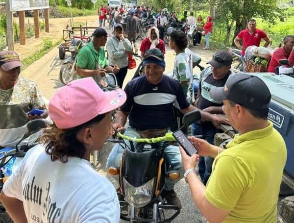 Foule de personnes et motos sur une route, illustrant les perturbations causées par la crise agricole en Colombie.