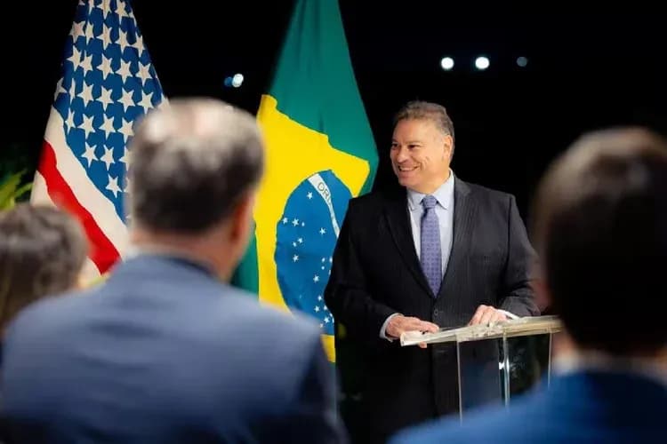 Gabriel Escobar, chargé d'affaires des États-Unis, devant les drapeaux américain et brésilien, symbolisant les relations commerciales et diplomatiques.