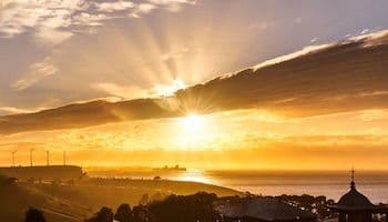 Golden sunrise over Rosario, Argentina, with the Paraná River and city skyline under a dramatic sky, symbolizing the city's dynamic climate.