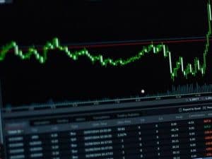 Graphique boursier vert sur fond noir, illustrant les fluctuations du prix du pétrole Brent et les tensions du marché.