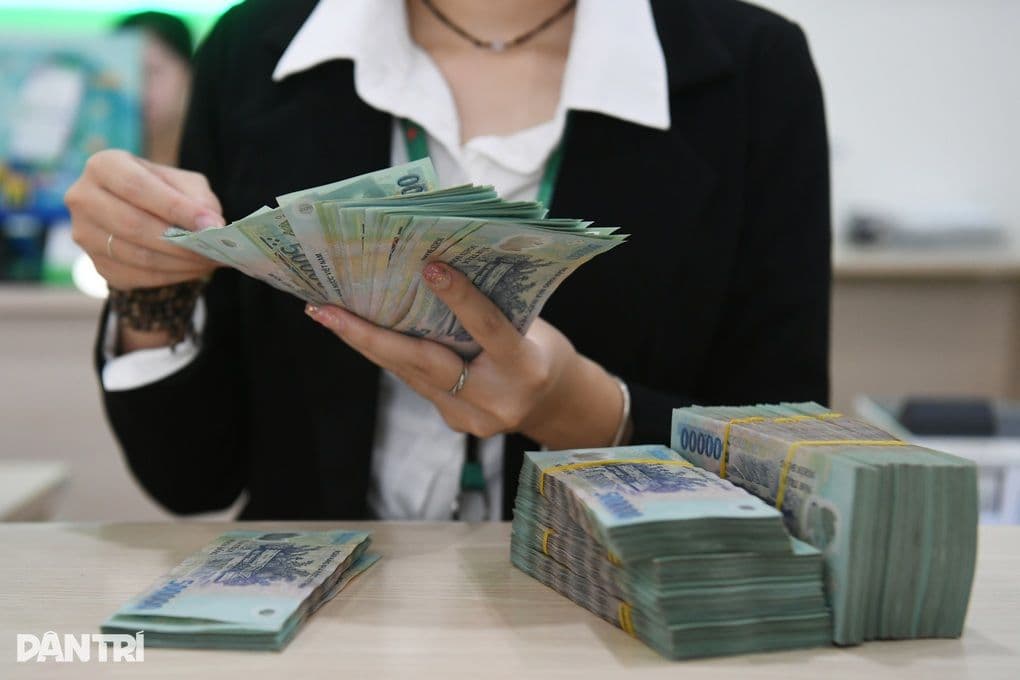 Hands counting stacks of Vietnamese Dong banknotes, symbolizing personal income and tax adjustments.