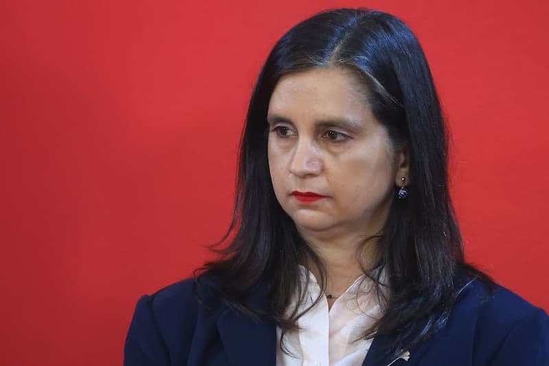 Ignacia Fernández, Minister of Agriculture, in a contemplative pose against a red background.