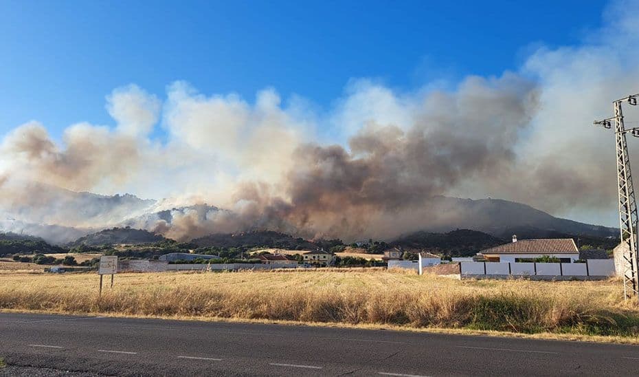Incendie de forêt majeur en Andalousie, avec d'épaisses fumées s'élevant au-dessus des collines et des habitations menacées en premier plan.