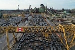 Industrie canadienne sous la menace des tarifs de Trump, avec des bobines d'acier et un drapeau canadien.