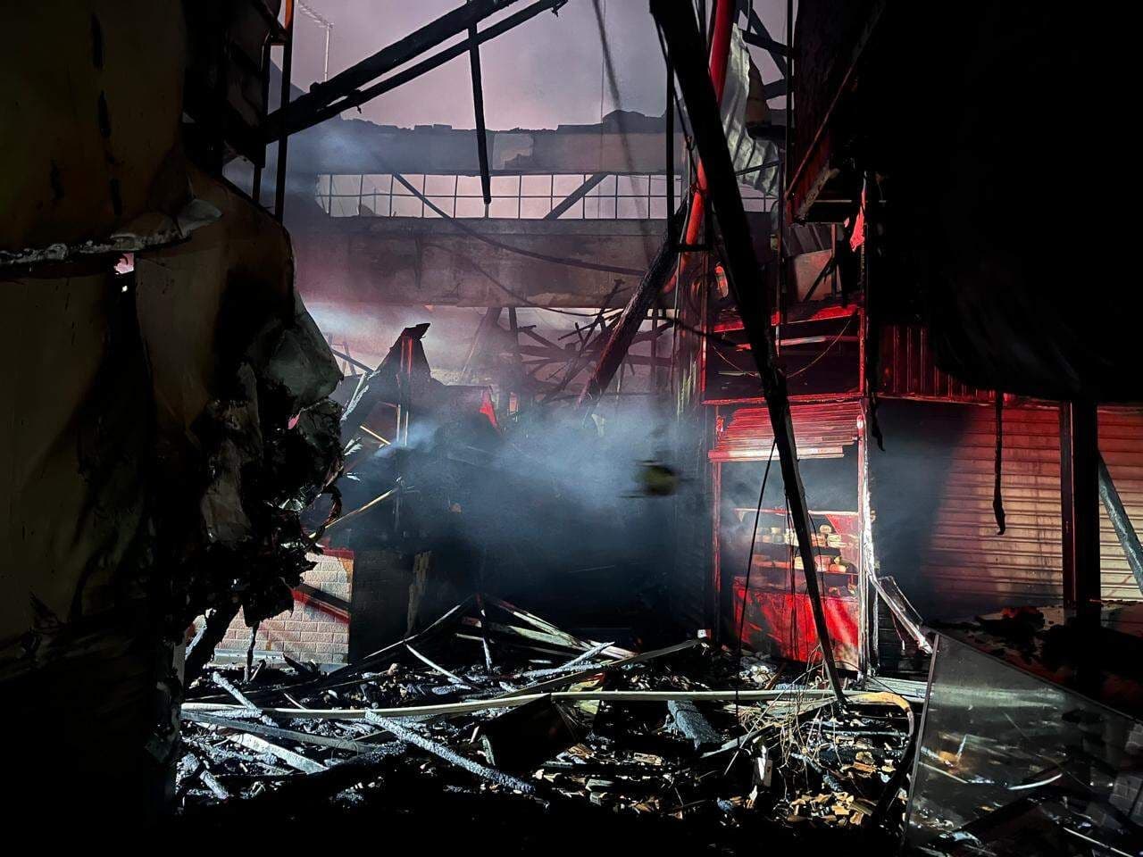 Intérieur du Mercado Municipal de Piracicaba après l'incendie, montrant les décombres, les structures effondrées et la fumée.