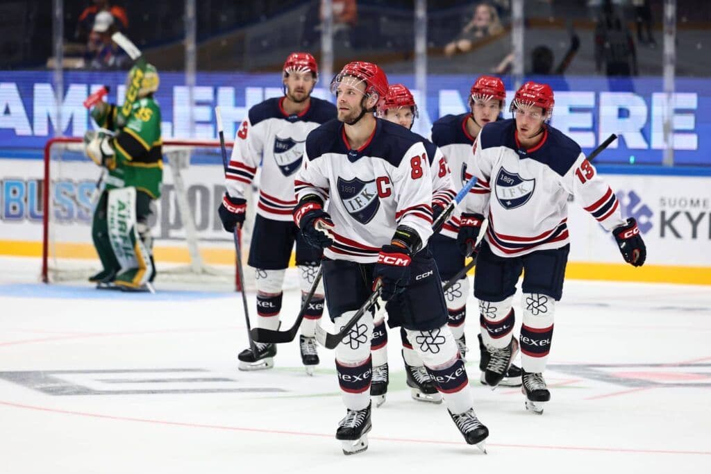 Joueurs de hockey sur glace finlandais en action sur la patinoire, représentant l'intensité du jeu en Mestis.