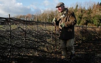 King Charles, the 'Gardener King,' inspecting his Highgrove Gardens with a shovel, demonstrating his personal involvement.