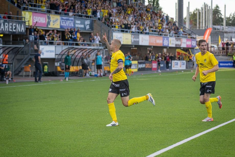 KuPS-pelaaja juhlii maaliaan täpötäydellä stadionilla, taustalla hurraavat fanit.