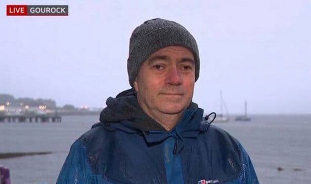 Le reporter Jamie McIvor de la BBC en direct sous la pluie battante lors d'une alerte météo.