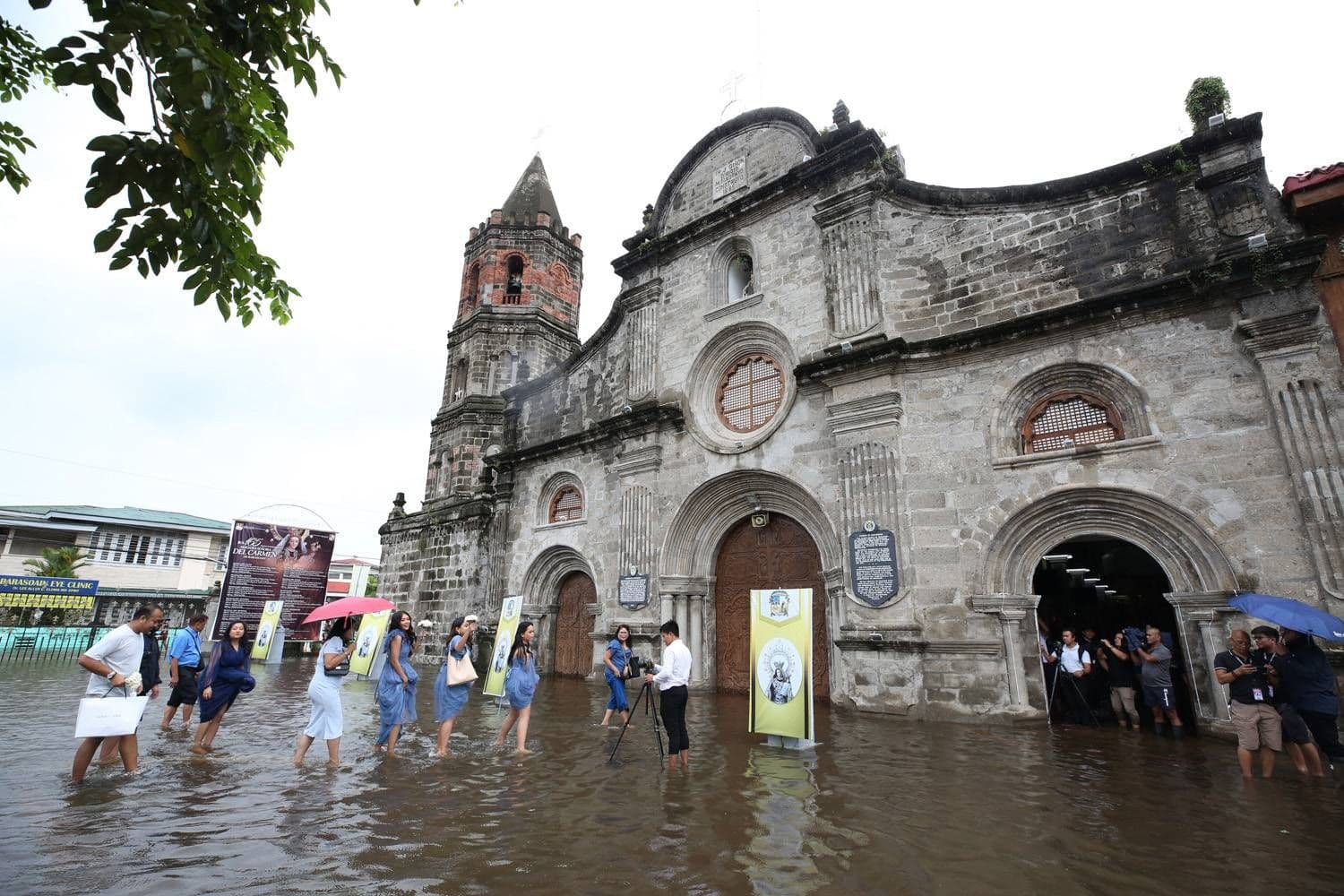 L'historique église de Barasoain à Malolos, Bulacan, submergée par les inondations, avec des fidèles traversant l'eau.