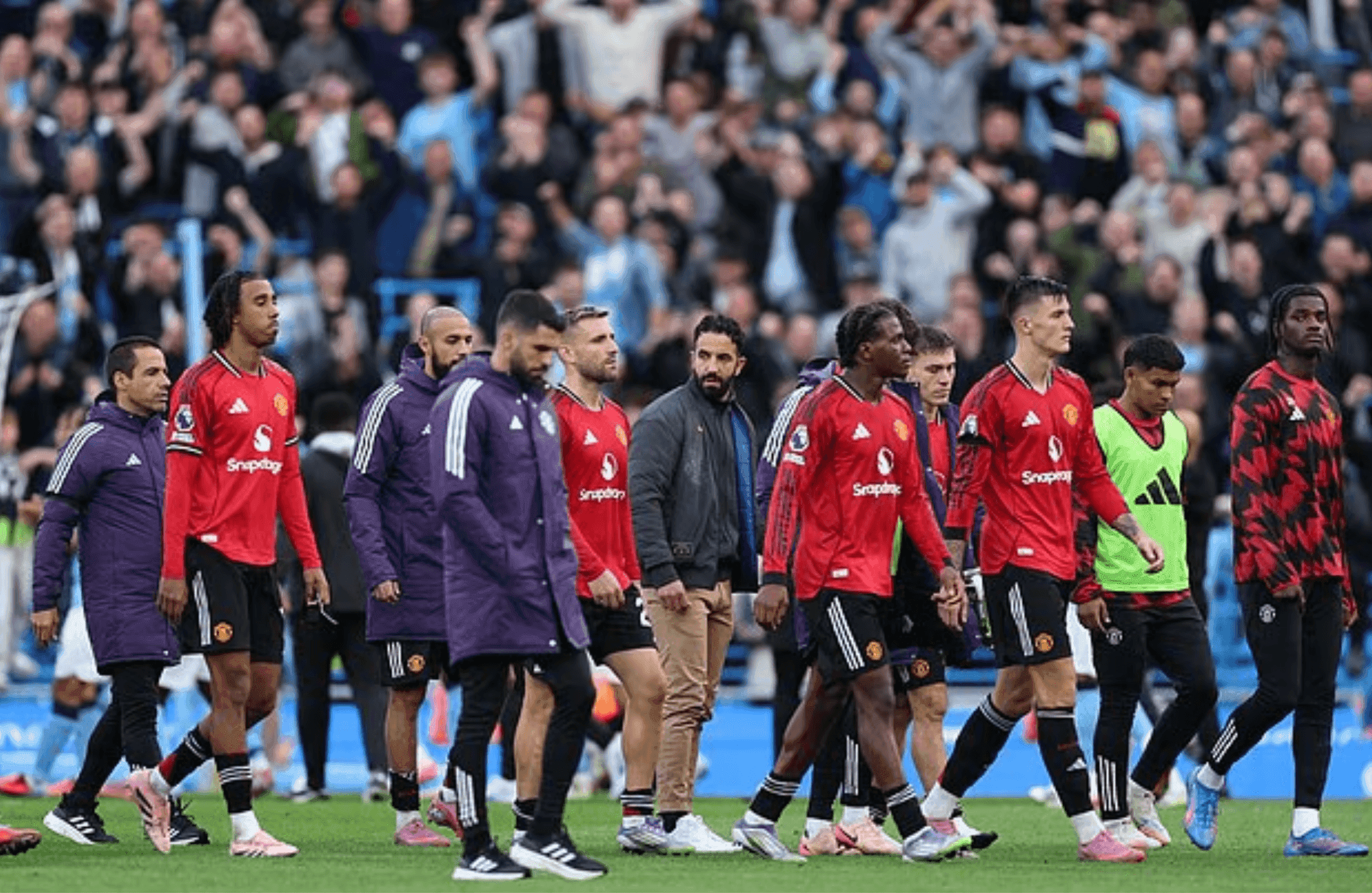 L'équipe et le staff de Manchester United, dont Ruben Amorim, quittant le terrain l'air abattu après une défaite.