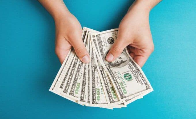 Mains tenant des billets de banque, symbolisant les économies et le pouvoir d'achat.