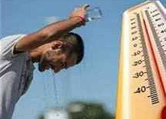 Man pouring water over his head to cool down, symbolizing the discomfort of Egypt's humid heat.