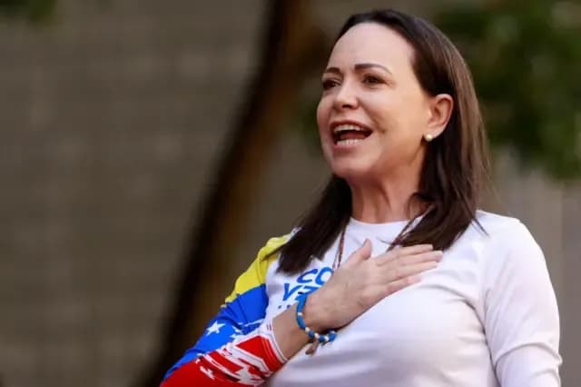 María Corina Machado, la main sur la poitrine, devant les couleurs du drapeau vénézuélien, incarnant l'unité de l'opposition.