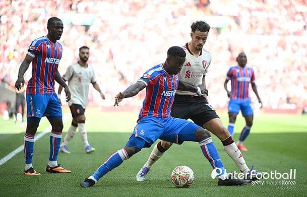 Marc Guéhi of Crystal Palace defending against an opponent in a red kit, showcasing his defensive prowess