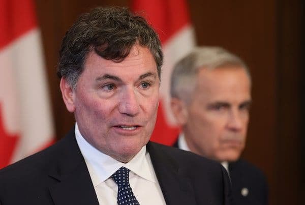 Mark Carney et un officiel canadien discutant des liens entre commerce et fentanyl, sur fond de drapeaux canadiens.