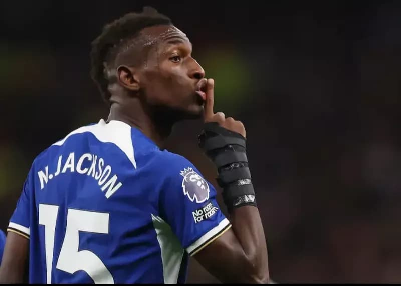 Nicolas Jackson, attaquant de Chelsea, faisant un geste de 'chut' sur le terrain, symbolisant la controverse autour de son transfert avorté.