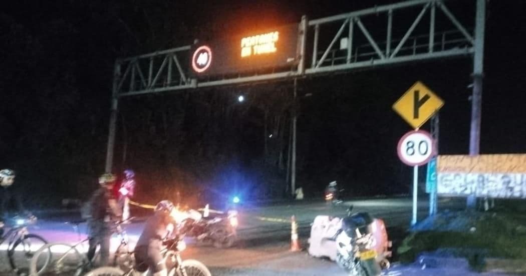 Nighttime view of a roadblock on the Vía al Llano highway in Colombia, caused by rice farmers' protests, with people and vehicles obstructing the road.