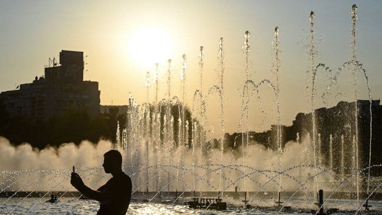 O persoană se răcorește lângă fântânile din București, simbolizând canicula verii în România.