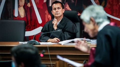 Oficial em vestes judiciais, possivelmente membro da CNE, simbolizando a autoridade na definição de diretivas eleitorais.