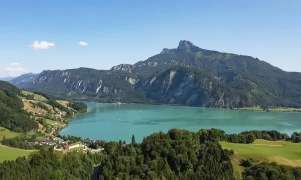Panoramic view of Mondsee lake in Austria's Salzkammergut region, surrounded by mountains and green shores.