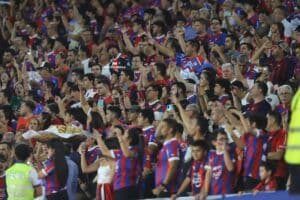 Passionate football fans in a packed stadium, creating an intense atmosphere for a Copa Libertadores match between Cerro Porteño and Estudiantes.