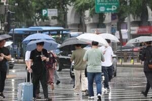 Pedestrians with umbrellas on a rainy street, symbolizing the intense, localized downpours, sometimes reaching 70mm per hour, experienced in various South Korean regions.