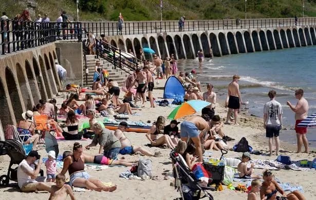 People enjoying a sunny beach in Folkestone, Kent, as warm weather returns to the UK.